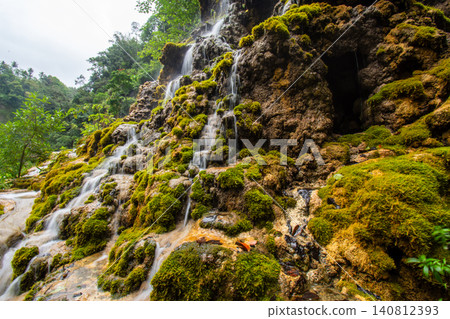 Beautiful silk effect waterfall flowing down mossy rock cliffs at Goa Tetes Lumajang Indonesia Beautiful silk effect waterfall flowing down mossy rock cliffs at Goa Tetes Lumajang Indonesia 140812393