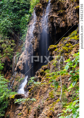 Beautiful silk effect waterfall flowing down mossy rock cliffs at Goa Tetes Lumajang Indonesia Beautiful silk effect waterfall flowing down mossy rock cliffs at Goa Tetes Lumajang Indonesia 140812398