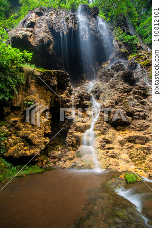 Beautiful silk effect waterfall flowing down mossy rock cliffs at Goa Tetes Lumajang Indonesia Beautiful silk effect waterfall flowing down mossy rock cliffs at Goa Tetes Lumajang Indonesia 140812401