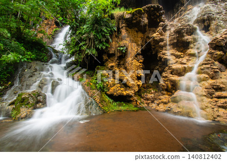 Beautiful silk effect waterfall flowing down mossy rock cliffs at Goa Tetes Lumajang Indonesia Beautiful silk effect waterfall flowing down mossy rock cliffs at Goa Tetes Lumajang Indonesia 140812402