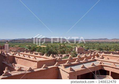The stepped battlements of the Kasbah Taourirt stand out against the backdrop of the vast green oasis in Ouarzazate, Morocco. 140812470