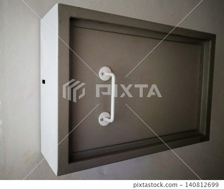 metal box of grey color with a white handle is fixed on a white wall metal box of grey color with a white handle is fixed on a white wall 140812699