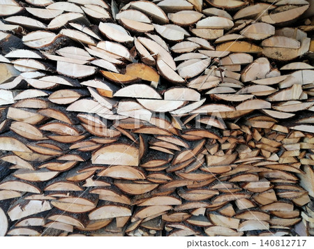 dense wall of chopped wooden logs of various sizes and shades 140812717