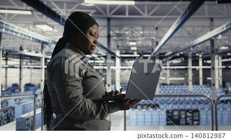 African american IT professional uses a laptop in a server room to review test results and confirm reliable system operation. African american IT professional uses a laptop in a server room to review test results and confirm reliable system operation. 140812987