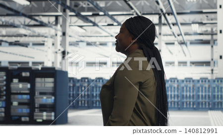 Data center manager oversees programmers reviewing AI diagnostics and machine learning systems. 140812991