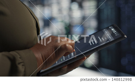 Programmer uses tablet in a data center to upgrade server hardware and improve workload capacity. Programmer uses tablet in a data center to upgrade server hardware and improve workload capacity. 140812998
