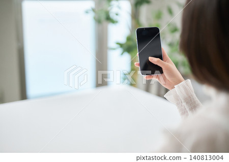 一位二十多歲的女性正在看她的智慧型手機。 一位二十多歲的女性正在看她的智慧型手機。 140813004