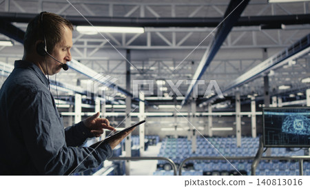 Data center technician uses tablet in a server room to help clients solve website hosting problems. Data center technician uses tablet in a server room to help clients solve website hosting problems. 140813016