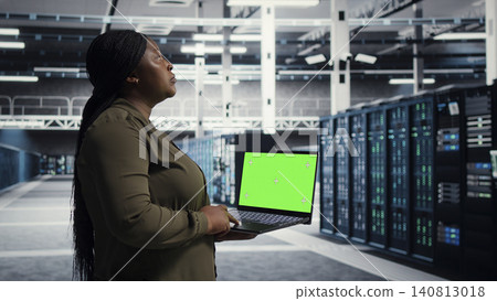 Data center administrator uses green screen laptop in a data center to inspect hardware and maintain system stability. Data center administrator uses green screen laptop in a data center to inspect hardware and maintain system stability. 140813018