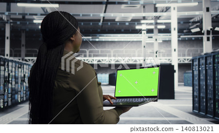 Data center engineer uses green screen laptop in a data center to inspect hardware and maintain system stability. Data center engineer uses green screen laptop in a data center to inspect hardware and maintain system stability. 140813021