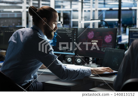 Technician works with a computer workstation in a server hub to support artificial intelligence systems. 140813152