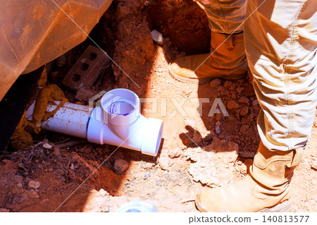 Construction workers are engaged in installing white waste pipe underground Construction workers are engaged in installing white waste pipe underground 140813577