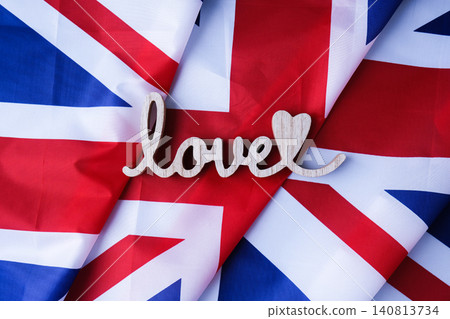 Wooden word love on National symbol of Great Britain. British full framed wave UK fabric flag background. Copy space for your text. Independence Wooden word love on National symbol of Great Britain. British full framed wave UK fabric flag background. Copy space for your text. Independence 140813734