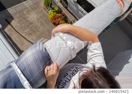 一位女士正在陽台上用褥夾晾曬褥子（俯視圖）。 140815421