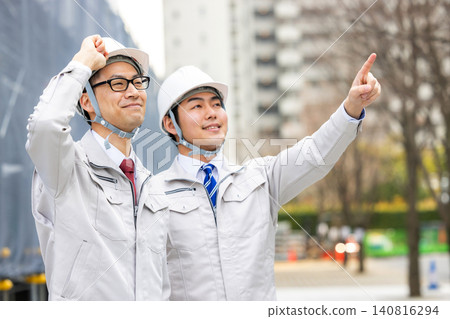 A man in work clothes points upwards. A man in work clothes points upwards. 140816294