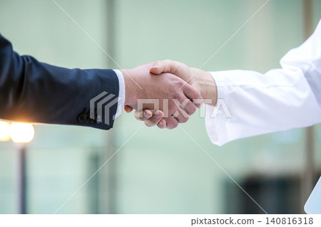 一位醫生和一位身穿白大褂的商人在醫院握手的醫學形象 140816318