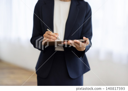 A close-up of a businesswoman's hands as she takes notes in a binder by the window. A close-up of a businesswoman's hands as she takes notes in a binder by the window. 140817393