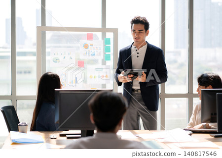 Businessman giving presentation on glass board, manager speaking to diverse team during meeting. Businessman giving presentation on glass board, manager speaking to diverse team during meeting. 140817546