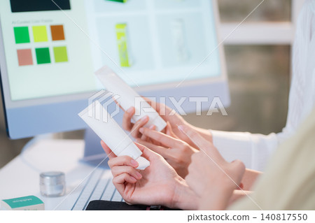 Two asian woman discussing cosmetic tube packaging sitting at modern home office. 140817550