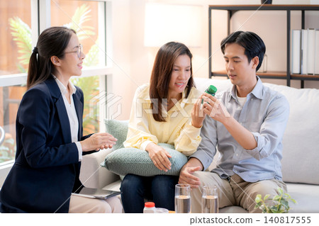 Asian young couple on sofa consulting with psychologist in living room at home. Asian young couple on sofa consulting with psychologist in living room at home. 140817555