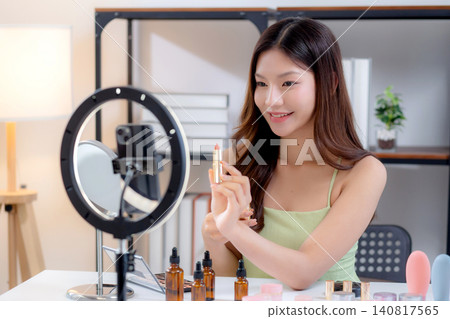 Young asian beauty influencer testing multiple lipstick shades on arm while recording makeup review. Young asian beauty influencer testing multiple lipstick shades on arm while recording makeup review. 140817565