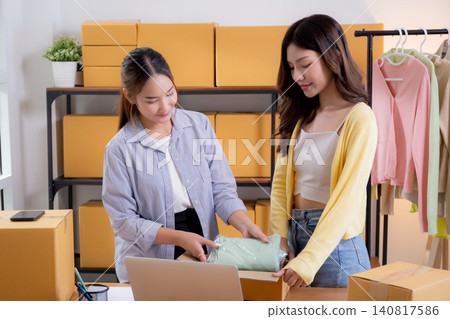 Two asian woman seller packing clothes product in cardboard box. Two asian woman seller packing clothes product in cardboard box. 140817586