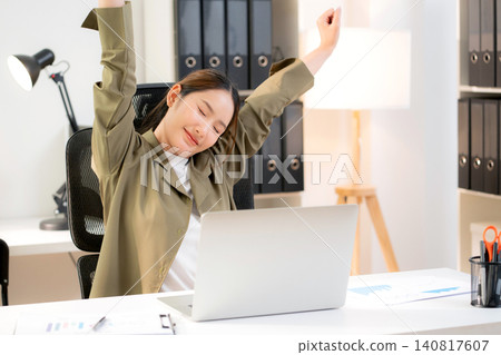 Asian businesswoman sitting at modern indoor office stretching her body and arms for relax. Asian businesswoman sitting at modern indoor office stretching her body and arms for relax. 140817607