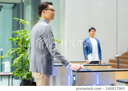 一位西裝革履的商人正從辦公室入口走過。圖片由Sky Perfect Tokyo Media Center提供。 一位西裝革履的商人正從辦公室入口走過。圖片由Sky Perfect Tokyo Media Center提供。 140817963