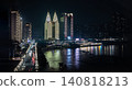 The Sheraton Chongqing Hotel's distinct, brightly lit golden towers serve as the brilliant centerpiece of the skyline, contrasting sharply against the dark night. The vibrant city lights and neon 140818213