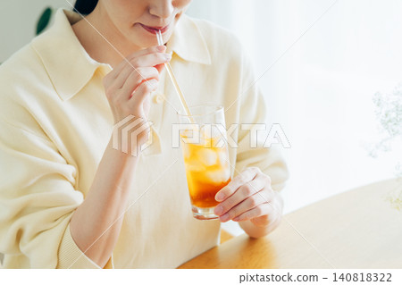 A young woman's hands as she drinks iced tea at home. A young woman's hands as she drinks iced tea at home. 140818322