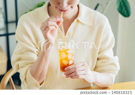 A young woman's hands as she drinks iced tea at home. A young woman's hands as she drinks iced tea at home. 140818323