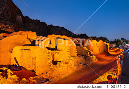 Night view of the historic mudbrick ruins and traditional architecture of AlUla Old Town illuminated by warm lights in Saudi Arabia. Night view of the historic mudbrick ruins and traditional architecture of AlUla Old Town illuminated by warm lights in Saudi Arabia. 140818342