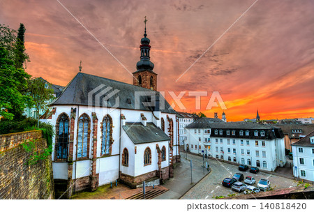The historic Schlosskirche Castle Church stands against a vibrant orange sunset sky in Saarbrucken, Germany. 140818420