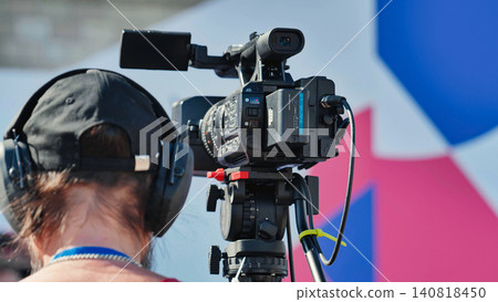 Videographer recording sport event with professional camera on tripod 140818450