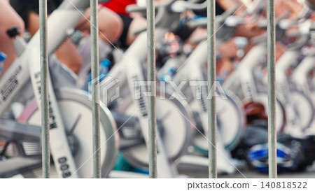 Athletes pedaling on exercise bikes during sports day behind a fence Athletes pedaling on exercise bikes during sports day behind a fence 140818522