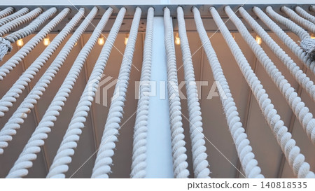 White nautical ropes hanging creating a repeating pattern with warm lights White nautical ropes hanging creating a repeating pattern with warm lights 140818535