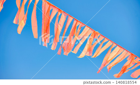 Orange prayer flags waving in the wind in India against a clear blue sky Orange prayer flags waving in the wind in India against a clear blue sky 140818554