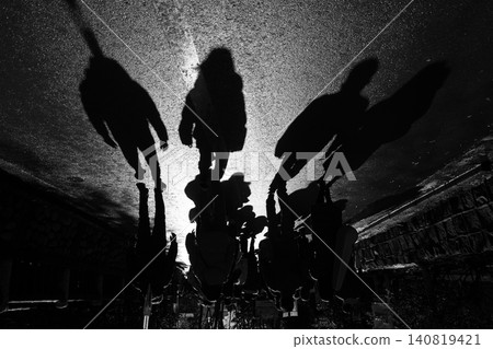 Long, drawn-out shadows of people on the asphalt road and a dramatic, monochrome landscape. Long, drawn-out shadows of people on the asphalt road and a dramatic, monochrome landscape. 140819421