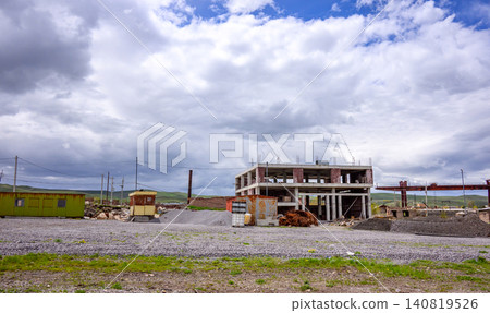Ruined building site with broken walls and scattered debris under overcast skies 140819526