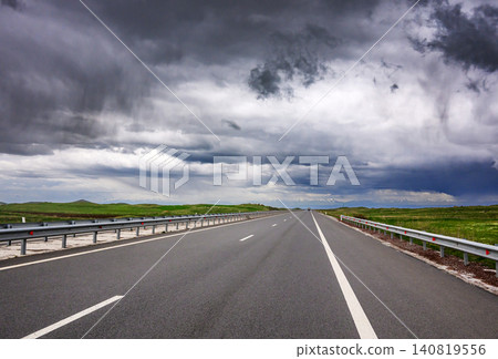 Storm clouds loom over empty asphalt road Storm clouds loom over empty asphalt road 140819556