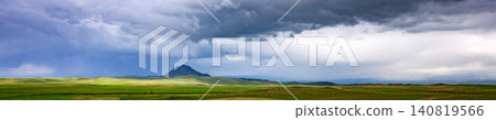 Storm clouds loom over rolling green hills and grassy plains Storm clouds loom over rolling green hills and grassy plains 140819566