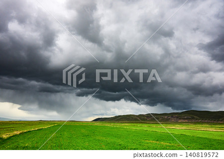 Stormy sky casts shadow over rolling green fields with no visible life forms Stormy sky casts shadow over rolling green fields with no visible life forms 140819572