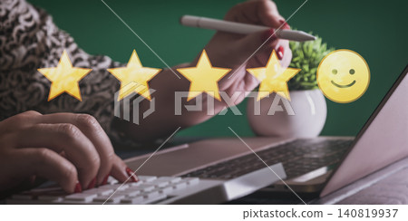 Customer satisfaction concept: Woman leaving an excellent 5-star rating and positive review on a laptop Customer satisfaction concept: Woman leaving an excellent 5-star rating and positive review on a laptop 140819937