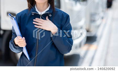 一名女子手放在胸前站立，背景中可以看到一輛卡車。 140820092
