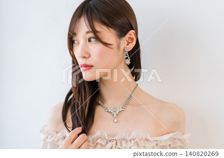 A young Asian woman in a dress, wearing a necklace and earrings. 140820269
