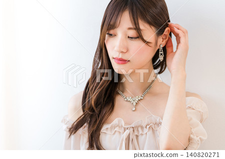 A young Asian woman in a dress, wearing a necklace and earrings. 140820271