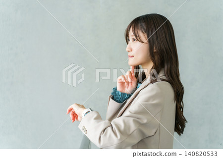 A businesswoman in a suit looking at a wristwatch or smartwatch A businesswoman in a suit looking at a wristwatch or smartwatch 140820533