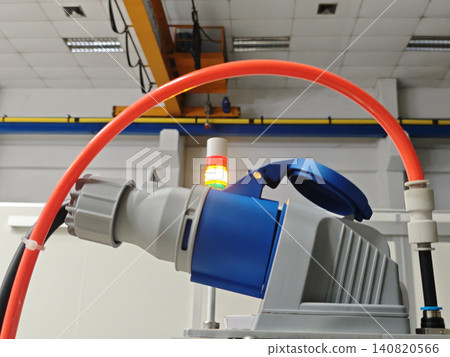 Industrial robot arm in factory with hose and warning light, automated machine in production hall Industrial robot arm in factory with hose and warning light, automated machine in production hall 140820566