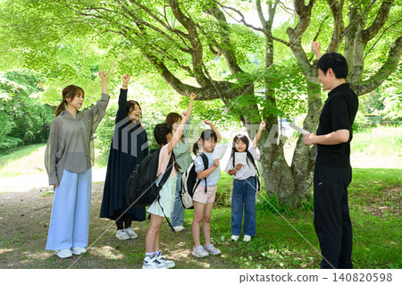 家庭和團體在鬱鬱蔥蔥的森林中徒步旅行和觀察自然,同時查看地圖。 家庭和團體在鬱鬱蔥蔥的森林中徒步旅行和觀察自然,同時查看地圖。 140820598