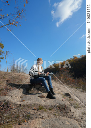 Beautiful blonde girl playing guitar ukulele and singing relaxing enjoying outdoors on sunny autumn day. Hippie woman in boho style training playing musical instrument. Fall leaves Beautiful blonde girl playing guitar ukulele and singing relaxing enjoying outdoors on sunny autumn day. Hippie woman in boho style training playing musical instrument. Fall leaves 140821531